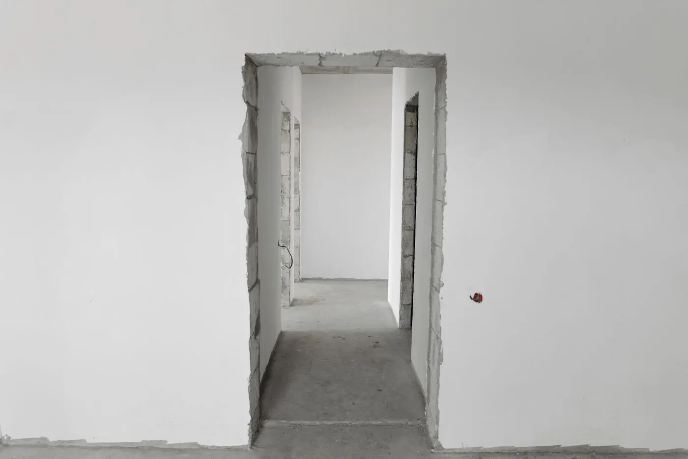 An unfinished interior partition wall, the block courses still showing in the door reveal before plastering
