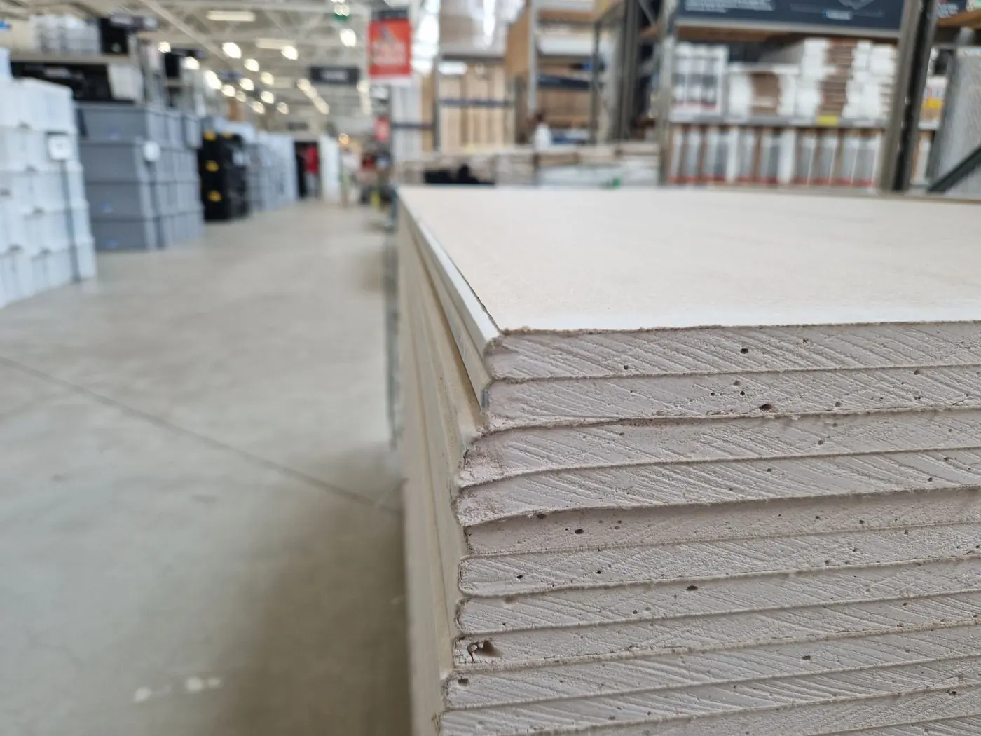 A stack of plasterboard seen along its edge, the chalky gypsum core showing between the paper faces